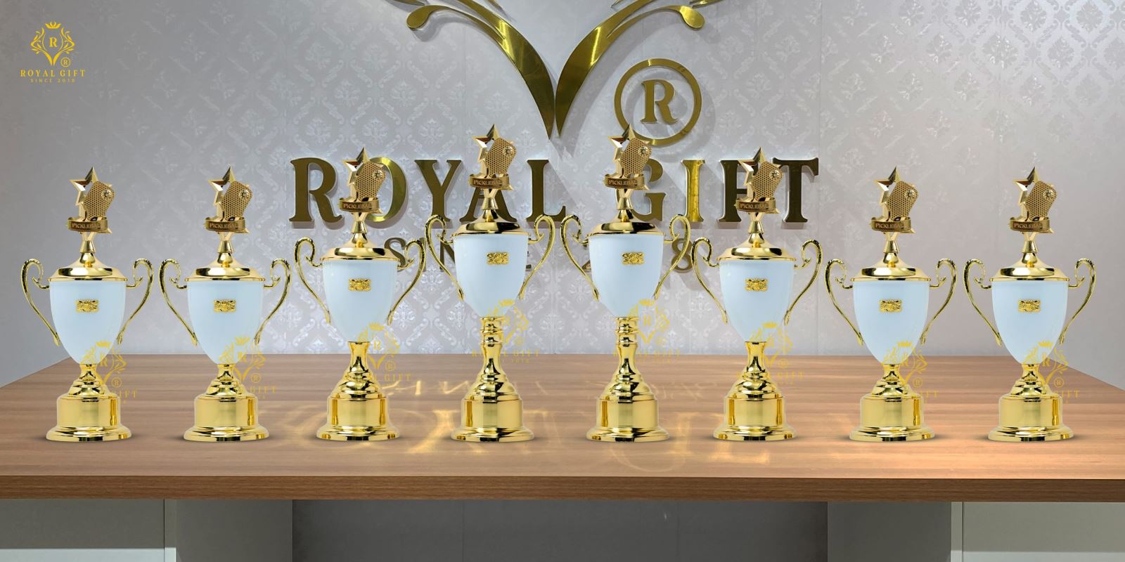 Nhiều bộ cúp Pickleball trắng ngọc phối vàng được Royal Gift trưng bày theo các kích cỡ